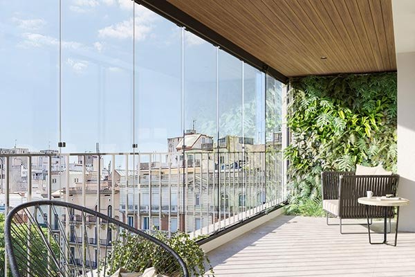Balcón acristalado con cortinas de cristal y vistas a la ciudad