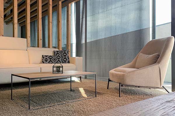 Salón moderno con cortinas enrollables tipo screen que filtran la luz