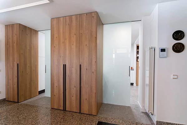 Puerta corredera de cristal opaco junto a armarios de madera